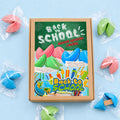 Kolorowe ciasteczka z wróżbą Back to School w transparentnych foliach, w kartoniku z ozdobną etykietą